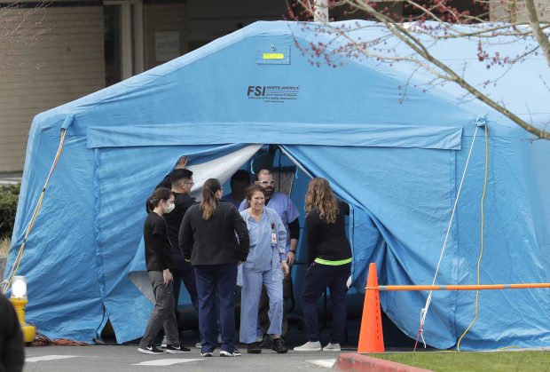 Workers exit a large tent set up in front of the emergency room at EvergreenHealth Medical Center, where Dr. David Siew ’98 experienced the first known outbreak of COVID-19 in the United States. —AP Photo/Ted S. Warren