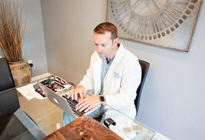 Zach Landman '08, a physician who specializes in pain medicine, spends hours in his home office on research and correspondence related to Lucy's condition. Photo by Kree Photography