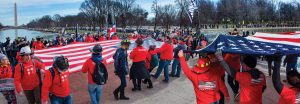 Firefighters taking part in a 2022 anti-vaccine mandate rally in Washington carry the U.S. flag from the Washington Monument toward the Lincoln Memorial in this digital montage.
