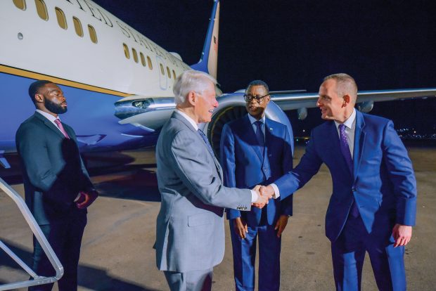 Ambassador Eric Kneedler, right, greets former President Bill Clinton in Rwanda.