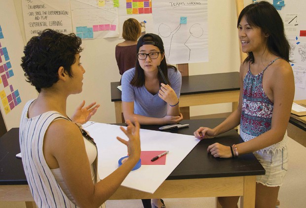 Students discuss at a desk at the Hive