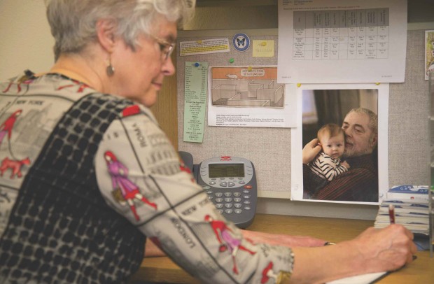 Peggy Arnold writes at her desk with a photo of Mogens Thomsen and his granddaughter