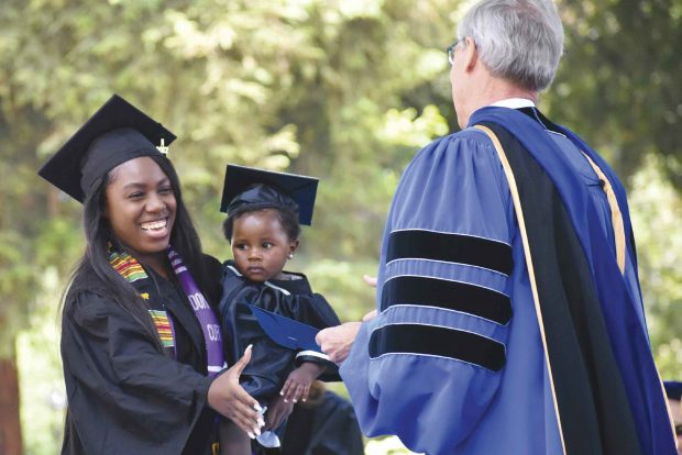 Class speaker Dominique Curtis ’17 brings her capped-and-gowned daughter with her to the stage to accept her diploma from President David Oxtoby.