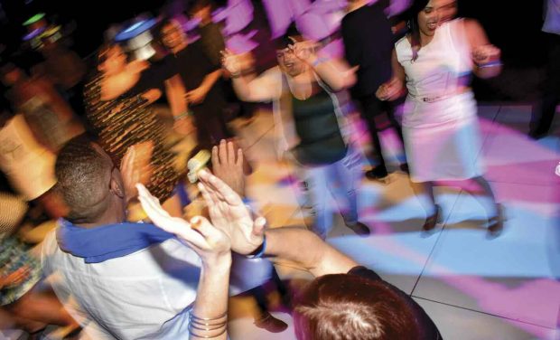 Dancers take over a lighted dance floor under the stars.