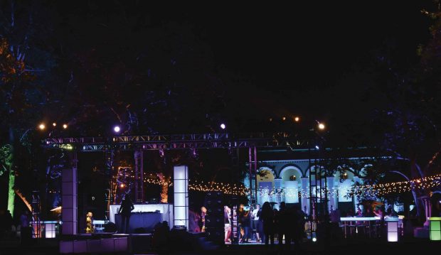 Dancers with a colorfully lit Bridges Auditorium in the background.