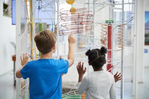 Two kids looking at a science exhibit, back view