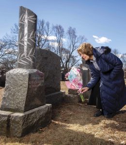 Ruth Craig ’74 places flowers on the grave of Adolfo Sartini, who died of the Spanish flu in 1918.