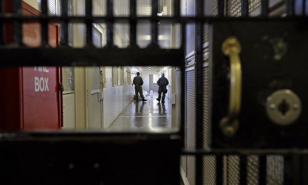 Prison guards stroll down a corridor at San Quentin State Prison in San Quentin, Calif.