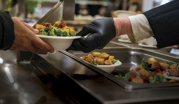 A Dining Service employee serves a student with a salad in a “Grab-and-Go” container.