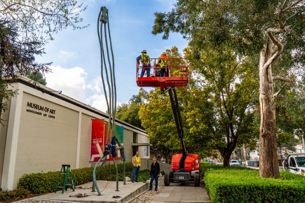 Workers survey the 30-foot sculpture ghandiG by Peter Shelton '73 at the museum's former location before moving it by crane across College Avenue to its new home.