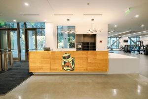 CARW Front Desk. Building entry to the left, original sagehen decal from repurposed maple court in center, Draper public fitness area on right.