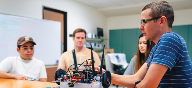 Kenneth Gonzalez ’24, Simon Heck ’22 and Liz Johnson ’24 work with Anthony Clark, assistant professor of computer science.