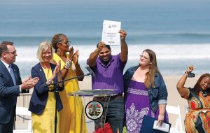 Anthony Bruce holds up a certificate of the deed as the family property taken by eminent domain in the 1920s is returned to descendants in 2022.