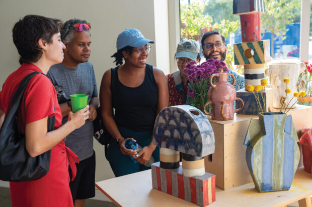 Becca Lofchie ’10 (left), returned to the College to give a gallery talk earlier this month. She and classmates view her collection of ceramic vases. Photo by: Daniel Klein ’26