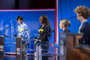Tene Ariyo ’26, center, stands in as a gubernatorial candidate during a dress rehearsal.