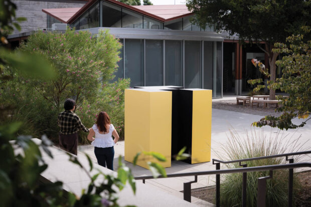 Yellow and black metal statue in a courtyard