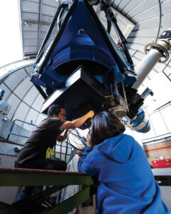 A professor and student work with a telescope