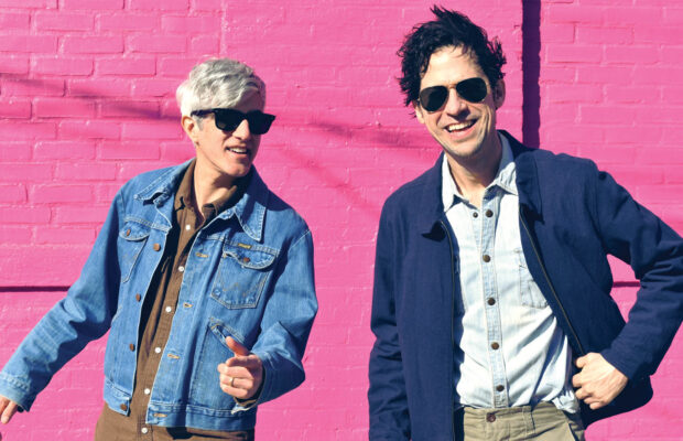 Portrait of We Are Scientists rock musicians against a pink wall